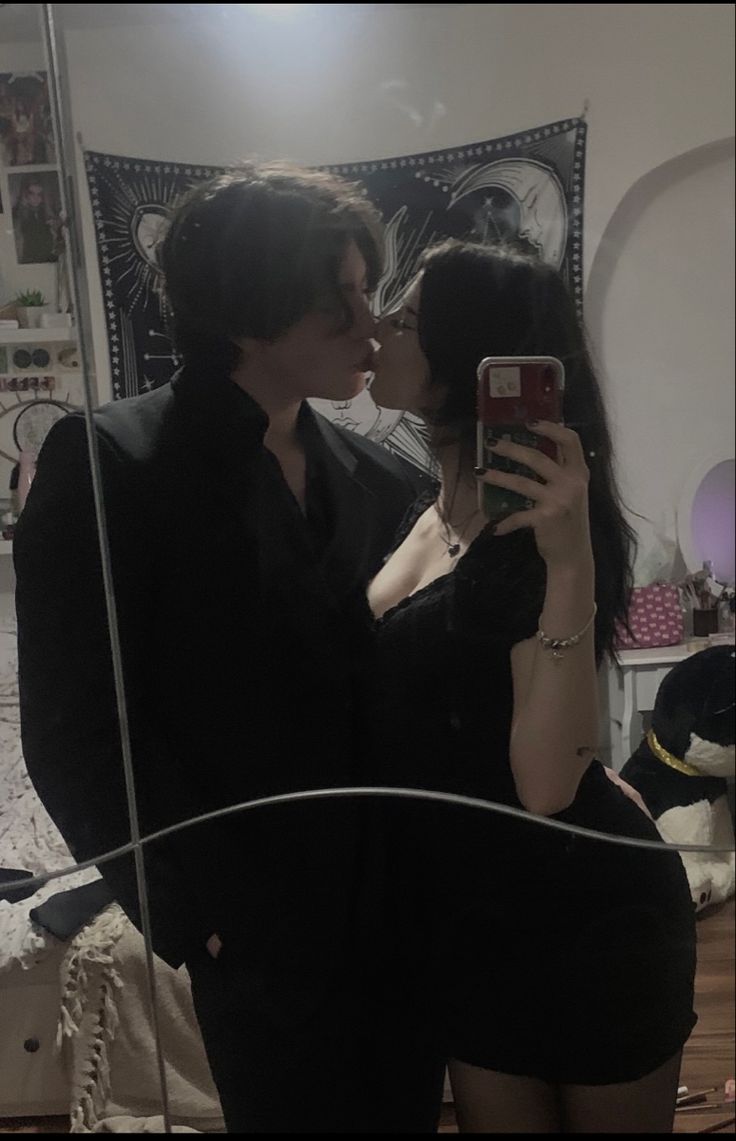 a man and woman kissing in front of a mirror