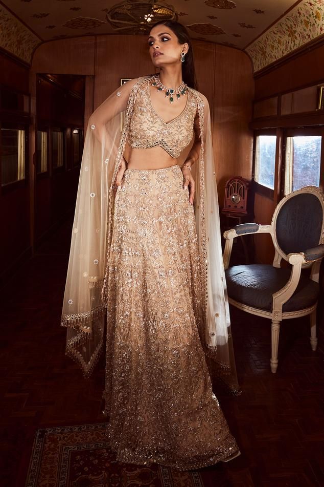 Beige can can attached lehenga with crystal embroidered intricate floral motifs. Comes with padded blouse and tasselled dupatta.
Components: 3
Pattern: Embroidered
Type Of Work: Crystal,Sequin
Neckline: V-neck
Sleeve Type: Sleeveless
Fabric: Net
Color: Beige
Other Details: 
Curved blouse hem
Lehenga Length: 44 inches
Note: Pink lehenga worn by the other model is not for sale
Occasion: Wedding,Bride - Aza Fashions Beige Mirror, Mirror Lehenga, Gold Lehenga, Mirror Work Lehenga, Raw Silk Lehenga, Net Lehenga, Tulle Sleeves, Pink Lehenga, Indian Bridal Dress