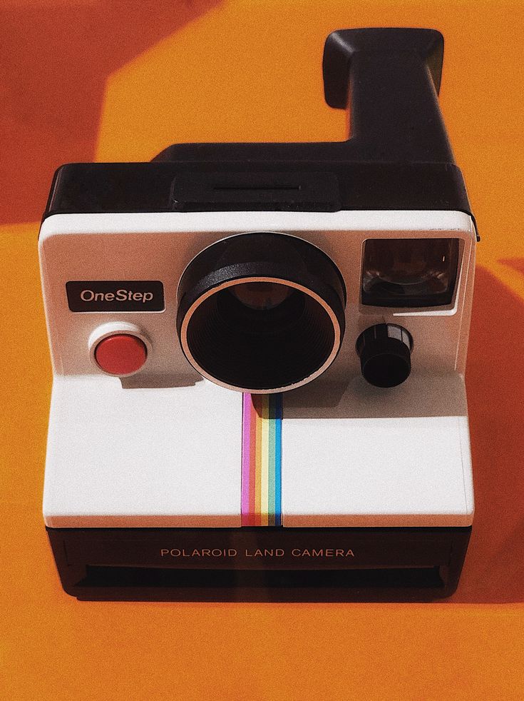 an old polaroid camera sitting on top of a table next to a yellow wall