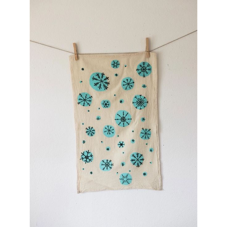 a teal and white wall hanging with snowflakes on it