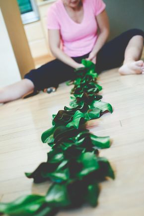 a woman sitting on the floor next to a green leafy plant that has been cut in half