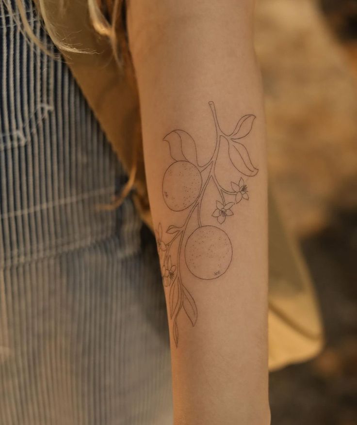 a woman with a tattoo on her arm holding onto a piece of paper that has fruit on it