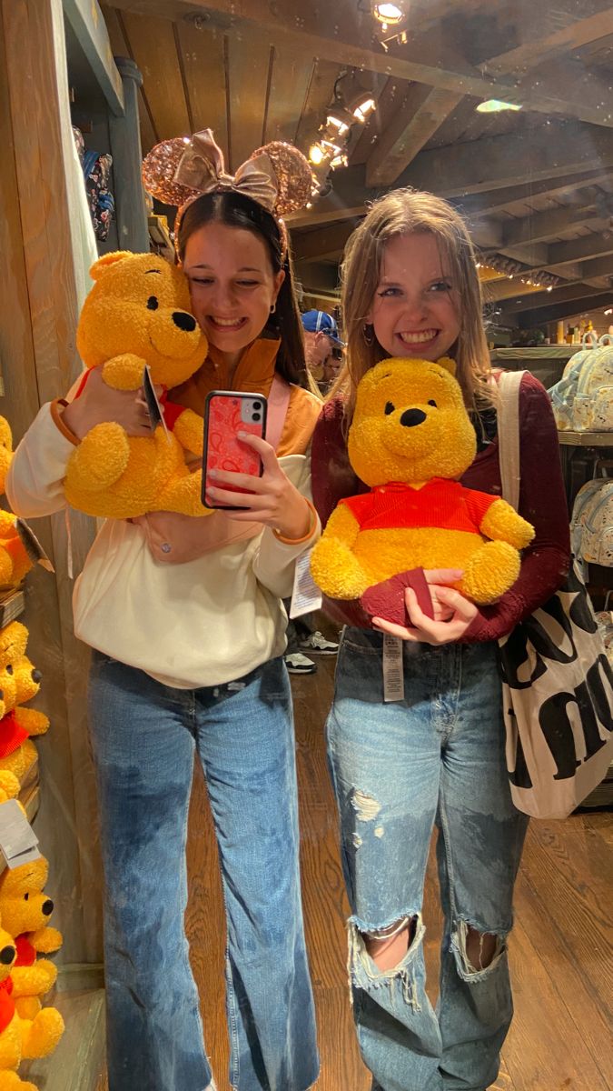 two girls holding up winnie the pooh stuffed animals