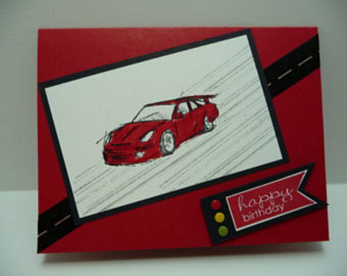 a card with a red car drawn on it and a happy birthday tag hanging from the front