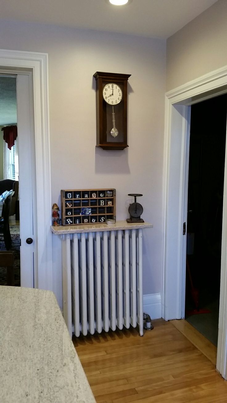 a room with a clock on the wall and a radiator next to it