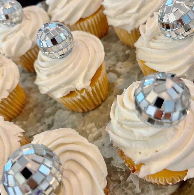 cupcakes with white frosting and disco balls on top