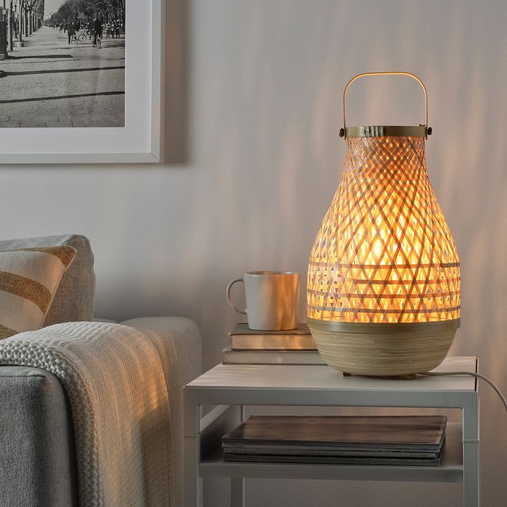 a table with a lamp on top of it next to a couch and coffee cup