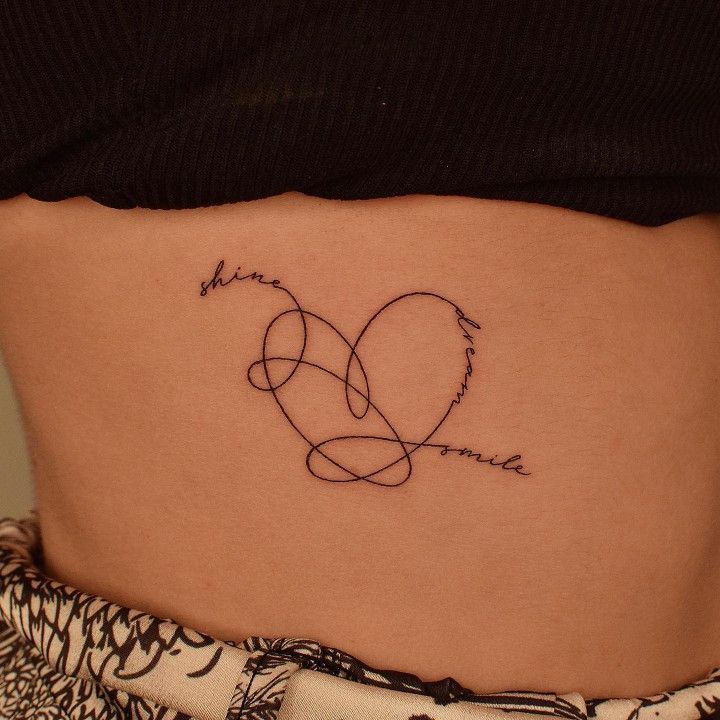 a woman's stomach with a heart tattoo on her lower back and the word love written in cursive writing