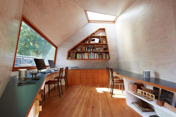 a room with wooden floors and shelves filled with books on top of each shelf in front of a window