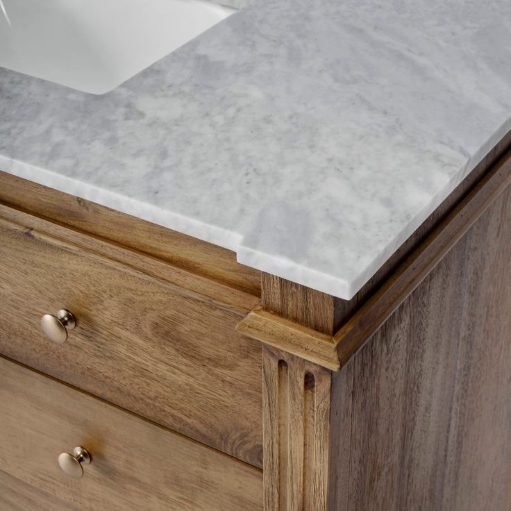 a white sink sitting on top of a wooden cabinet next to a counter with drawers