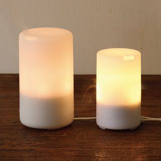 two white candles sitting on top of a wooden table