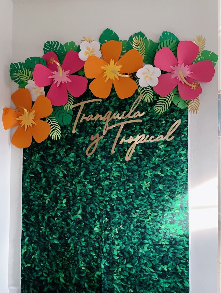 there is a green wall with flowers on it and the words tropics of tropical spelled in gold