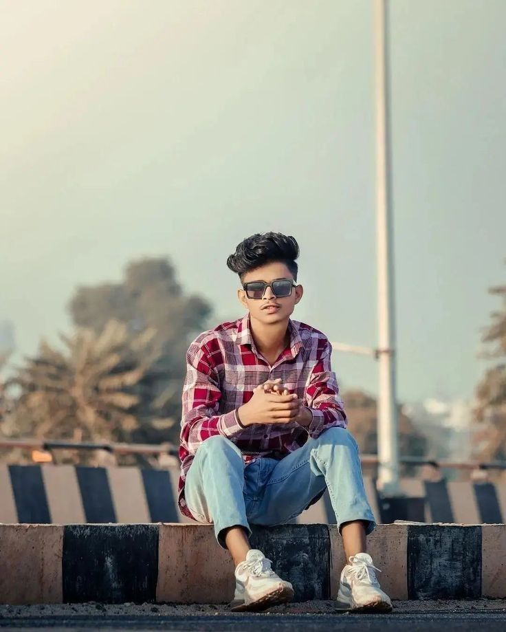 a young man sitting on the side of a road