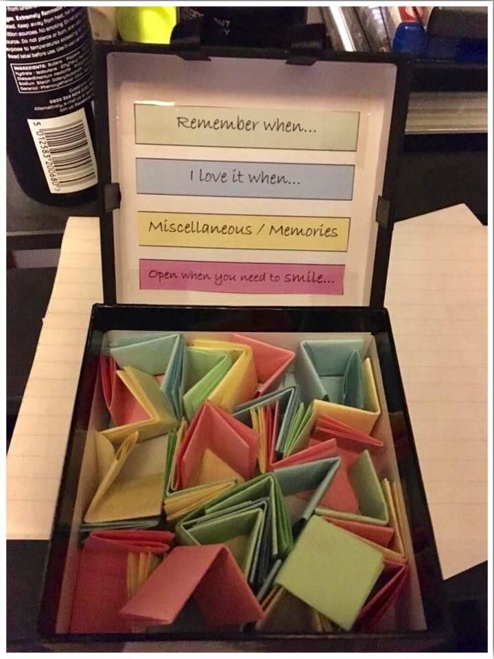 a box filled with lots of different colored origami pieces next to a note pad