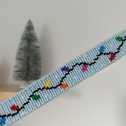 there is a beaded bracelet with colorful beads on it and a christmas tree in the background