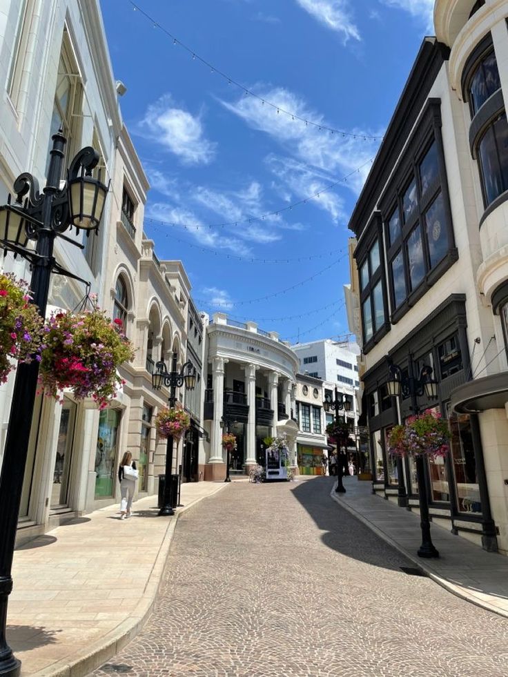 an empty street lined with tall buildings under a blue sky