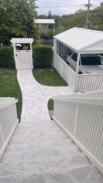 a white walkway leading to some houses with cars parked in the driveway and on the other side