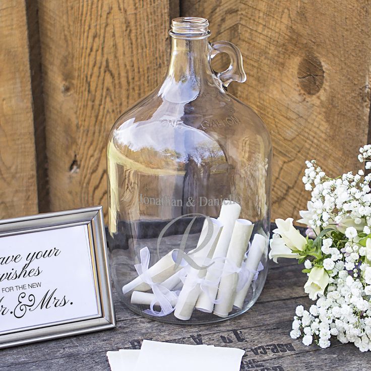 a glass bottle with some candles in it next to a sign and flowers on a table