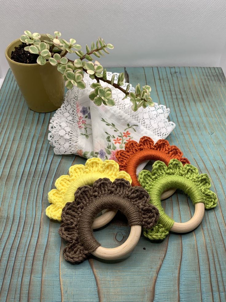 four crocheted rings sitting on top of a table next to a potted plant