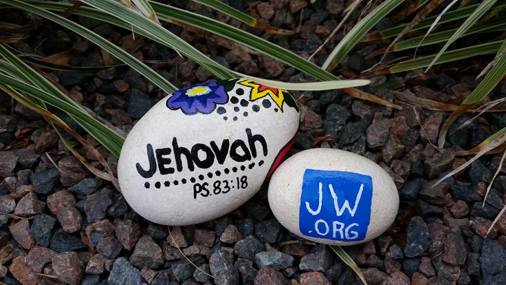 two rocks with the name jehovah painted on them sitting in some gravel