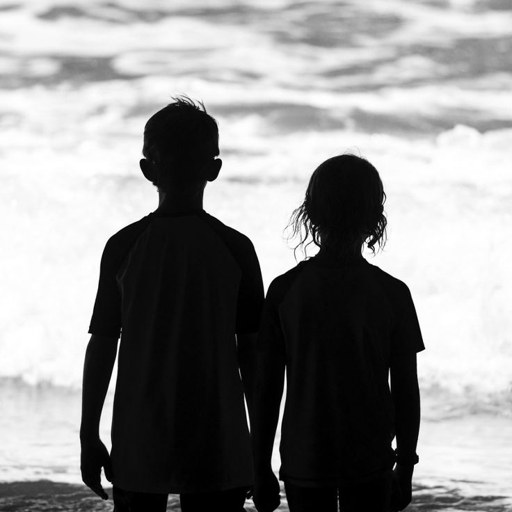 two people standing in front of the ocean