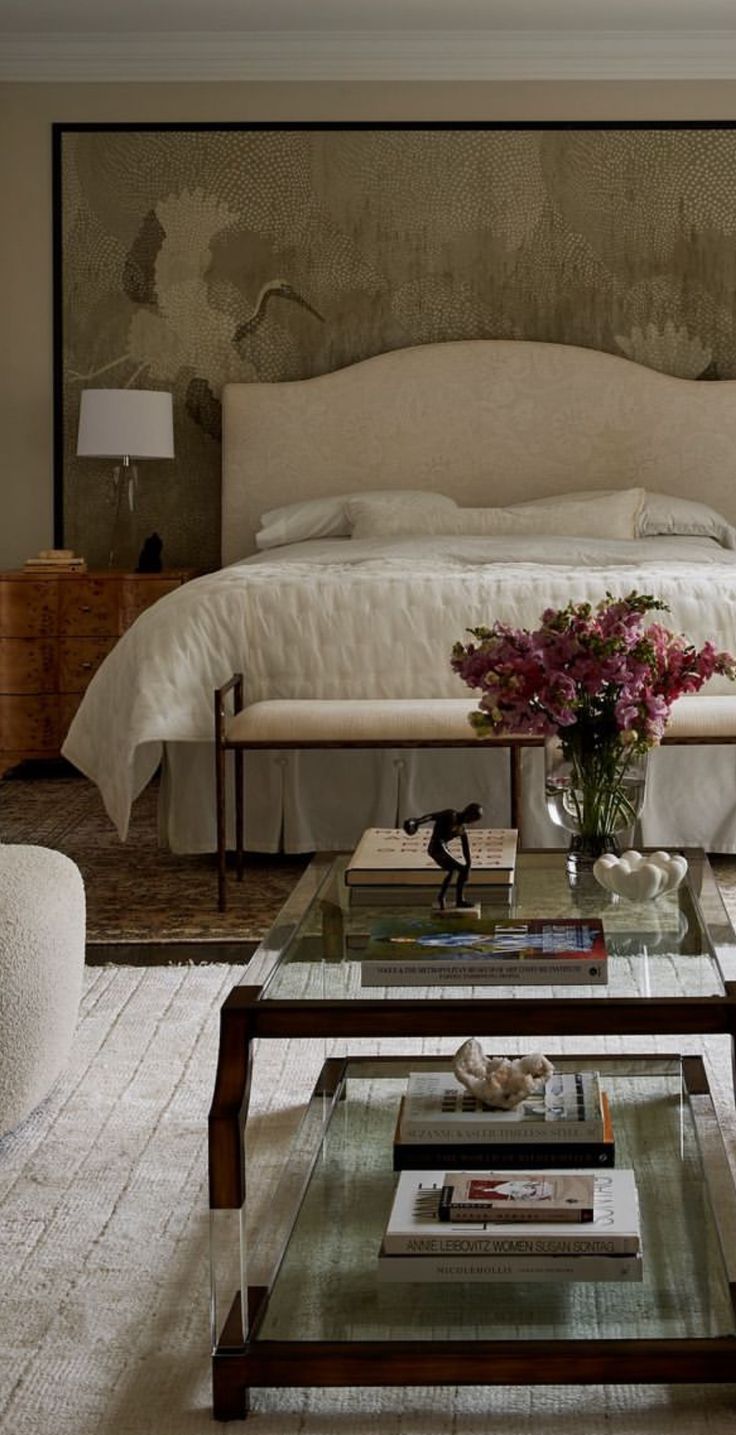 a bed sitting next to a table with flowers on top of it in a bedroom