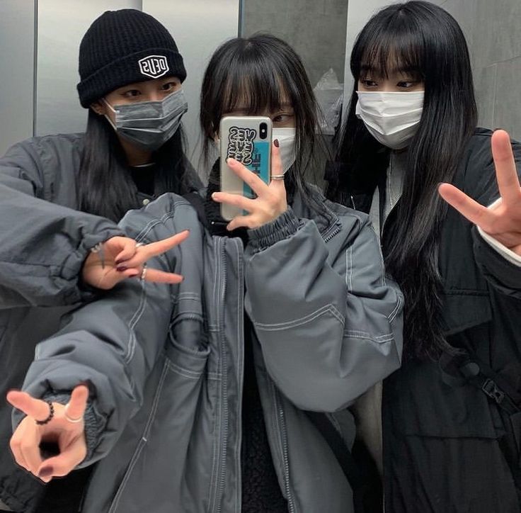 three girls wearing face masks and holding up their hands