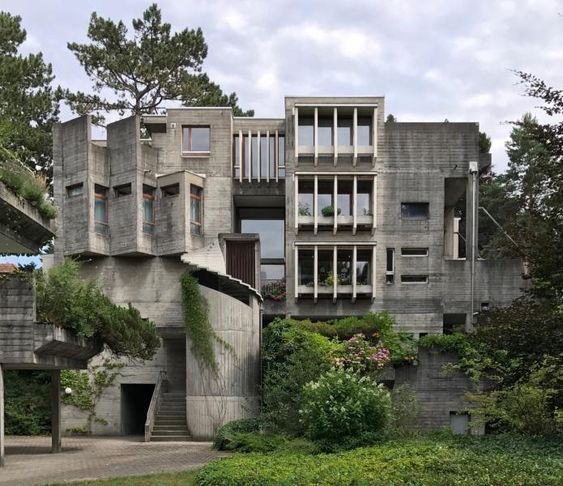 an unusual building with many windows and plants growing on it