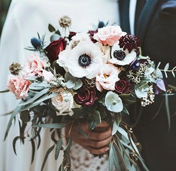 a bride and groom holding a bouquet of flowers in their hands, close up shot