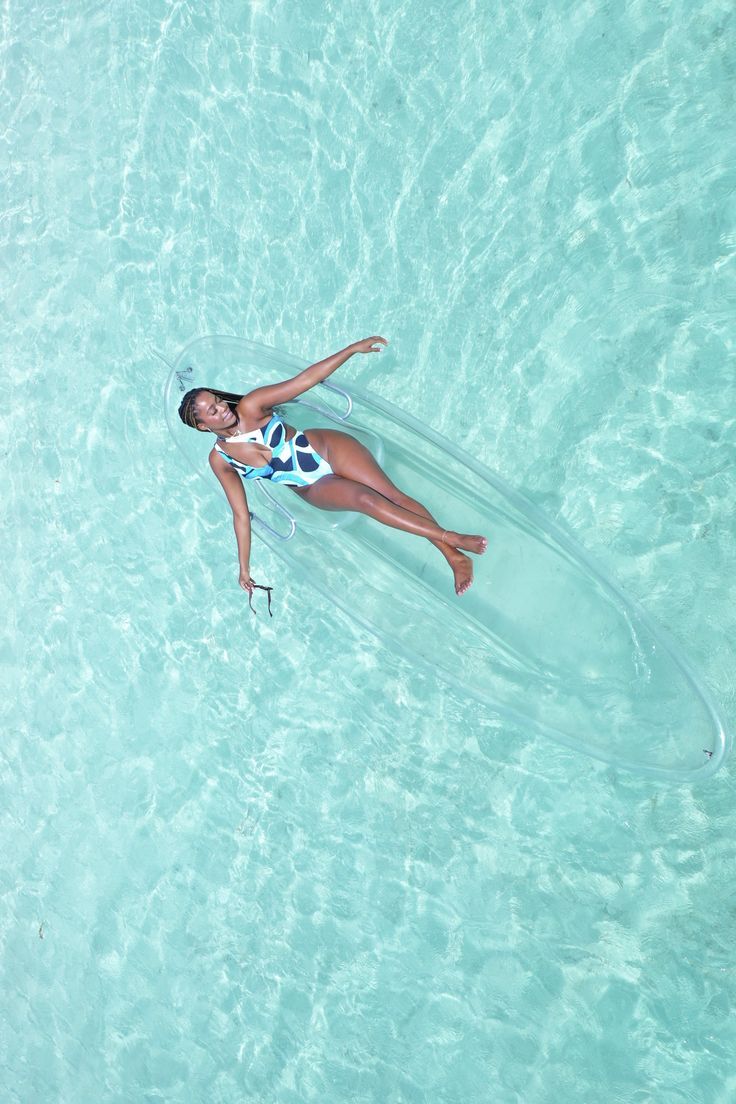 a woman floating in the ocean on top of a surfboard