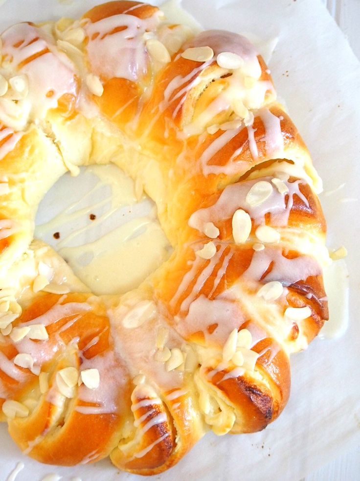 a white plate topped with a pastry covered in icing and almonds on top of a table