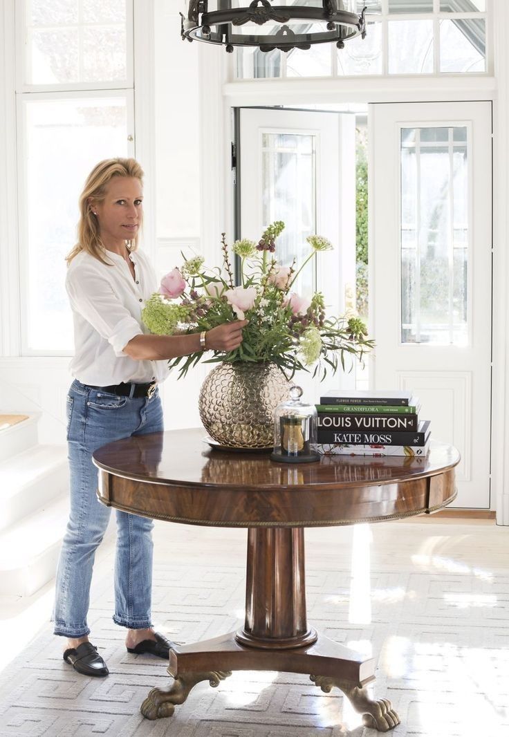 a woman standing next to a table with flowers on it and a pineapple vase