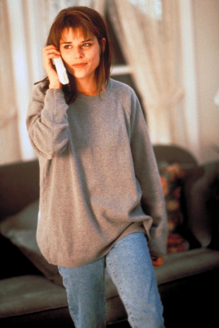 a woman talking on a cell phone while standing in a living room