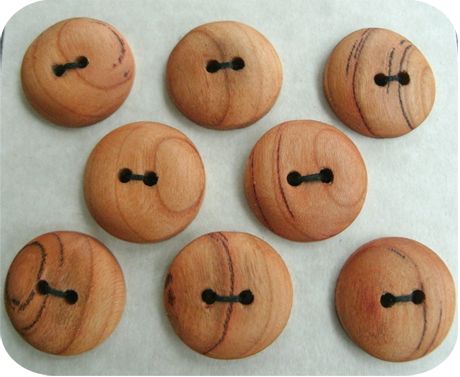 six wooden buttons with holes in them on a piece of paper