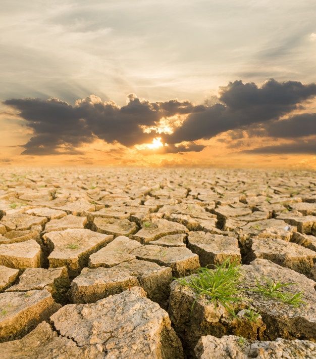 the sun is setting over a cracked field