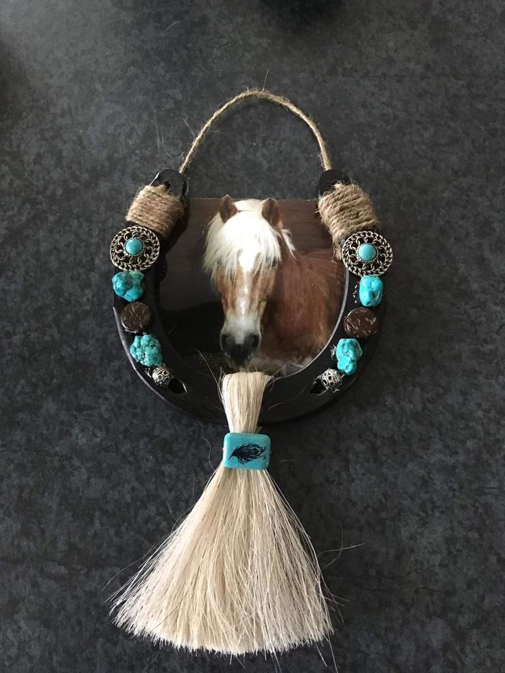 a brown and white horse is hanging from a mirror with tassels on it