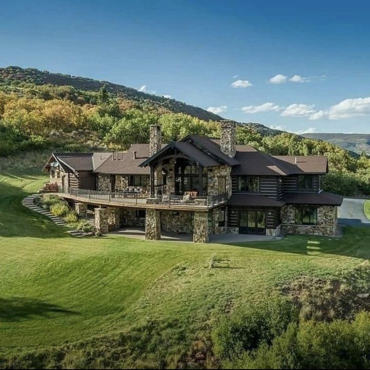 this is an aerial view of a large home in the mountains with green grass and trees