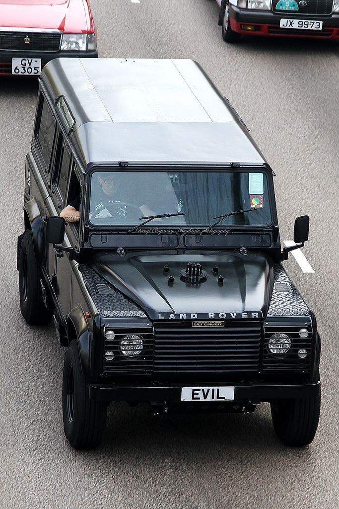 a black land rover is driving down the road