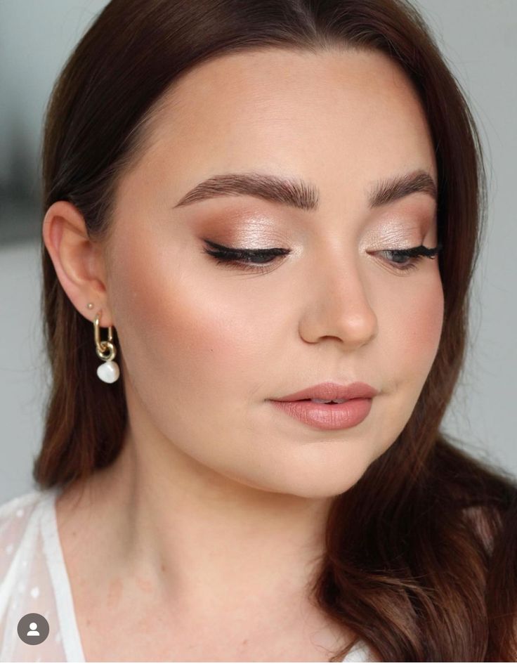 a woman with long brown hair wearing gold and white makeup