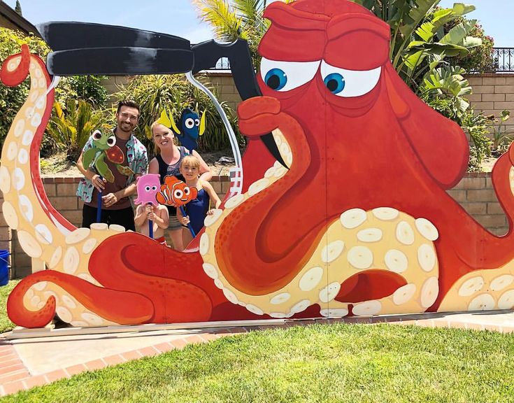 three people standing in front of a giant octopus sculpture with two children sitting on it