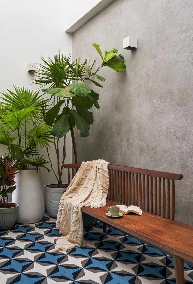 a wooden bench sitting next to a potted plant on top of a tiled floor