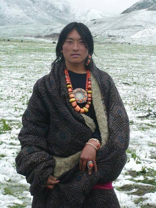 a woman standing in the snow with her hand on her hip and wearing an ethnic necklace