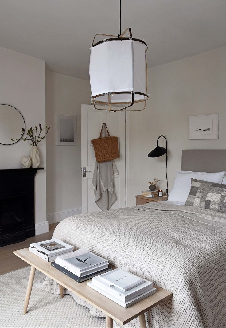 a bedroom with a bed, table and lamp hanging from it's ceiling in front of a fireplace