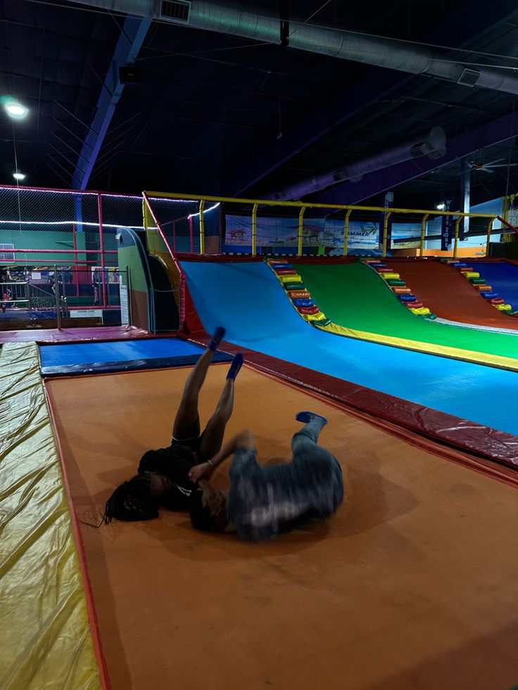 a person is laying on the ground in an indoor trampoline park with slides