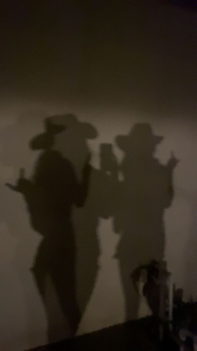 the shadow of two people standing next to each other in front of a gray wall