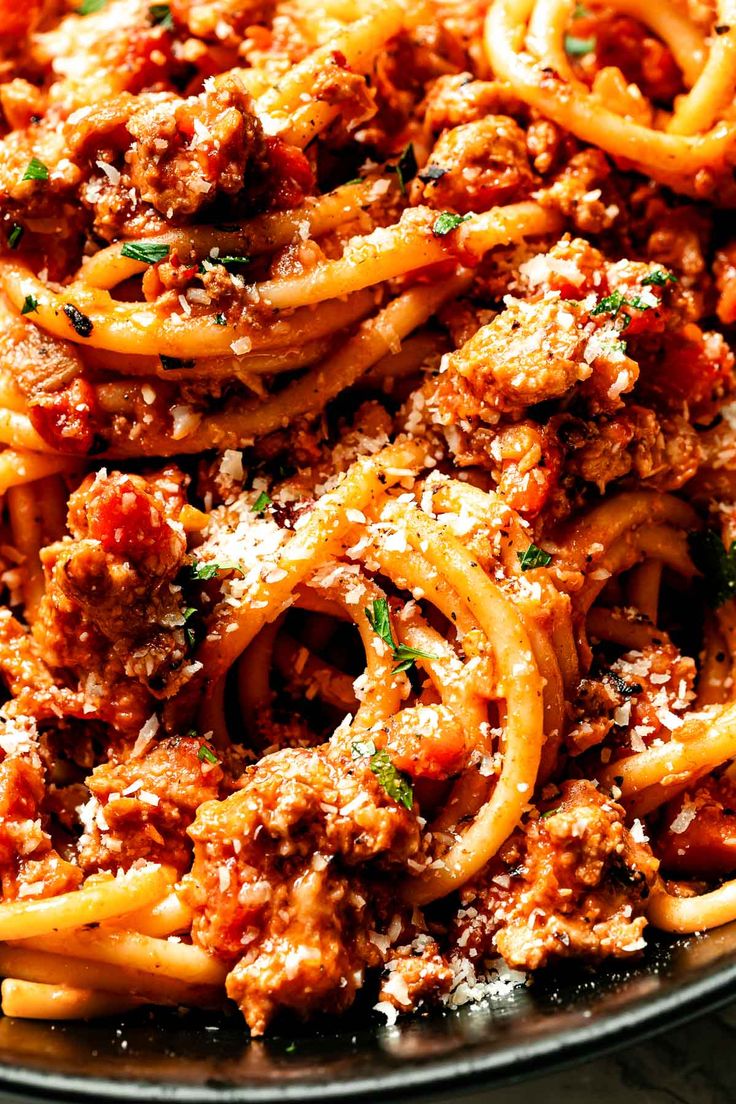 a plate full of spaghetti with meat sauce and parmesan cheese