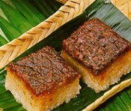 two pieces of food sitting on top of a green leaf covered plate with chopsticks