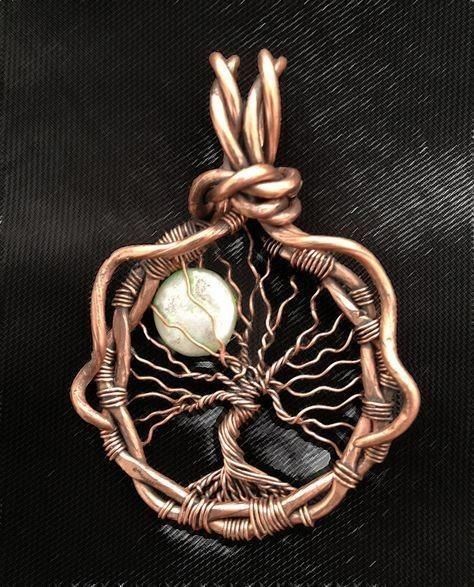 a tree of life pendant with a white stone in the center on a black background