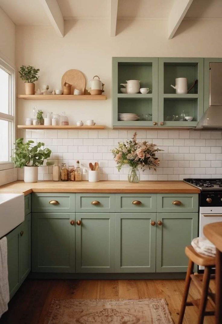 a kitchen with green cabinets and wooden counter tops in the center, along with potted plants on shelves