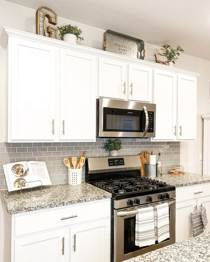 a kitchen with white cabinets and granite counter tops, stainless steel stove top oven and microwave